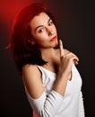 Portrait of mature good looking brunette woman in white blouse standing sideways gesturing silence sign with finger Royalty Free Stock Photo