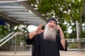 Happy mature handsome bearded hipster man talking on the phone and waving hand outside the subway train station Royalty Free Stock Photo