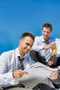 Portrait of mature handsome businessman reading newspaper against collegue during break Royalty Free Stock Photo