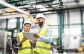 A portrait of an industrial man and woman engineer with tablet in a factory, talking. Royalty Free Stock Photo