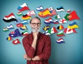 Portrait of mature interpreter and flags of different countries on blue background Royalty Free Stock Photo