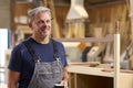 Portrait Of Mature Male Carpenter With Pencil Behind Ear And Hot Drink In Furniture Workshop Royalty Free Stock Photo