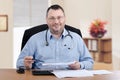 Portrait of mature male doctor sitting at the desk