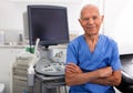 Portrait of mature male sonographer doctor in uniform in medical diagnostics office