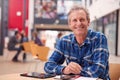 Portrait Of Mature Male Teacher Or Student With Digital Tablet Working At Table In College Hall Royalty Free Stock Photo