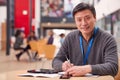 Portrait Of Mature Male Teacher Or Student With Digital Tablet Working At Table In College Hall Royalty Free Stock Photo