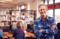 Portrait Of Mature Male Teacher Or Student In Library With Other Students Studying In Background Royalty Free Stock Photo