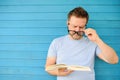 Portrait of mature man with big black eye glasses trying to read book but having difficulties seeing text because of vision Royalty Free Stock Photo