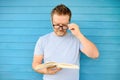 Portrait of mature man with big black eye glasses trying to read book but having difficulties seeing text because of vision Royalty Free Stock Photo