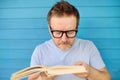 Portrait of mature man with big black eye glasses trying to read book but having difficulties seeing text because of vision Royalty Free Stock Photo