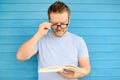 Portrait of mature man with big black eye glasses trying to read book but having difficulties seeing text because of vision Royalty Free Stock Photo