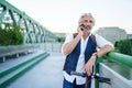 Portrait of mature man with electric scooter outdoors in city, using smartphone. Royalty Free Stock Photo