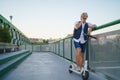 Portrait of mature man with electric scooter outdoors in city, using smartphone. Royalty Free Stock Photo