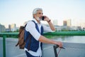 Portrait of mature man with electric scooter outdoors in city, using smartphone. Royalty Free Stock Photo