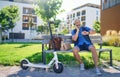 Portrait of mature man with electric scooter sitting outdoors in city, using smartphone. Royalty Free Stock Photo