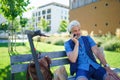 Portrait of mature man with electric scooter sitting outdoors in city, using smartphone. Royalty Free Stock Photo