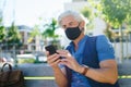 Portrait of mature man with face mask sitting outdoors in city, coronavirus concept. Royalty Free Stock Photo