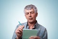 A portrait of mature man with gray hair wearing jean stylish shirt holding notebook and pen in his hands making some notes having Royalty Free Stock Photo