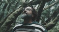 Portrait of mature man looking up with forest woods trees green ambient in background. Close up of male people in nature outdoors