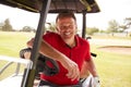 Portrait Of Mature Man Playing Golf Driving Buggy Along Course To Green On Red Letter Day