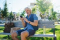 Portrait of mature man sitting outdoors on bench in city, using smartphone. Royalty Free Stock Photo