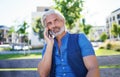 Portrait of mature man sitting outdoors in city, using smartphone. Royalty Free Stock Photo