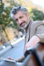 Portrait of mature man sitting on public bench