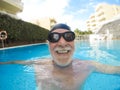Portrait of mature man smiling and looking at the camera in the pool having fun alone - training and swimming happy - close up of Royalty Free Stock Photo