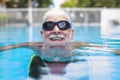 Portrait of mature man smiling and looking at the camera in the pool having fun alone - training and swimming happy - close up of Royalty Free Stock Photo