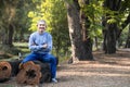 portrait mature man spend leisure time sitting on a log in the forest park Royalty Free Stock Photo