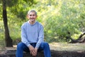 portrait mature man spend leisure time sitting on a log in the forest park Royalty Free Stock Photo