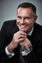 Portrait of mature man, tuxedo and smile, handsome face and serious isolated on grey background in studio. Luxury