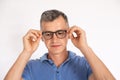 Portrait of mature man wearing blue T-shirt putting on glasses Royalty Free Stock Photo