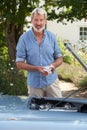 Portrait Of Mature Man Working On Engine Under Hood Of  Restored Classic Sports Car Outdoors Royalty Free Stock Photo