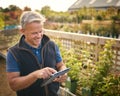 Portrait Of Mature Man Working Outdoors In Garden Centre Using Digital Tablet Royalty Free Stock Photo