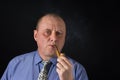 Portrait of mature office clerk smocking tobacco pipe against black background