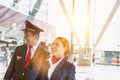 Portrait of mature pilot and attractive flight attendant walking while smiling in airport