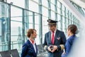 Portrait of Mature pilot talking to flight attendants in airport with yellow lens flare Royalty Free Stock Photo