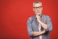 Portrait of a mature serious businessman wearing glasses isolated against red background. Happy senior man looking at camera with Royalty Free Stock Photo