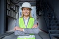 Portrait of mature successful female engineer, worker in hard hat and reflective vest with crossed arms smiling and Royalty Free Stock Photo