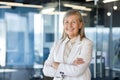 Portrait of mature successful senior woman boss inside office in business suit, businesswoman smiling and looking at Royalty Free Stock Photo