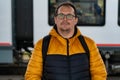 Portrait of mature unshaven plus size traveler with backpack on station platform against background of passing train Royalty Free Stock Photo