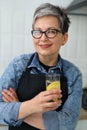 Portrait of a mature woman with a glass of lemon water in the home kitchen Royalty Free Stock Photo