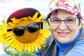 Portrait of mature woman with her friend big sunflower in sunglasses against the sky Royalty Free Stock Photo