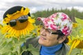 Portrait of mature woman with her friend big sunflower in sunglasses against the sky Royalty Free Stock Photo