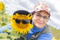 Portrait of mature woman with her friend big sunflower in sunglasses against the sky Royalty Free Stock Photo