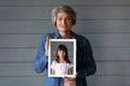 Portrait of mature woman hold picture of young herself