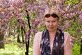 Portrait of mature woman near a decorative apple tree, which bloom Royalty Free Stock Photo