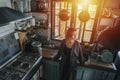 Portrait of mature woman in an old narrow cluttered kitchen at sunset