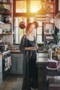 Portrait of a mature woman in an old narrow cluttered kitchen at sunset